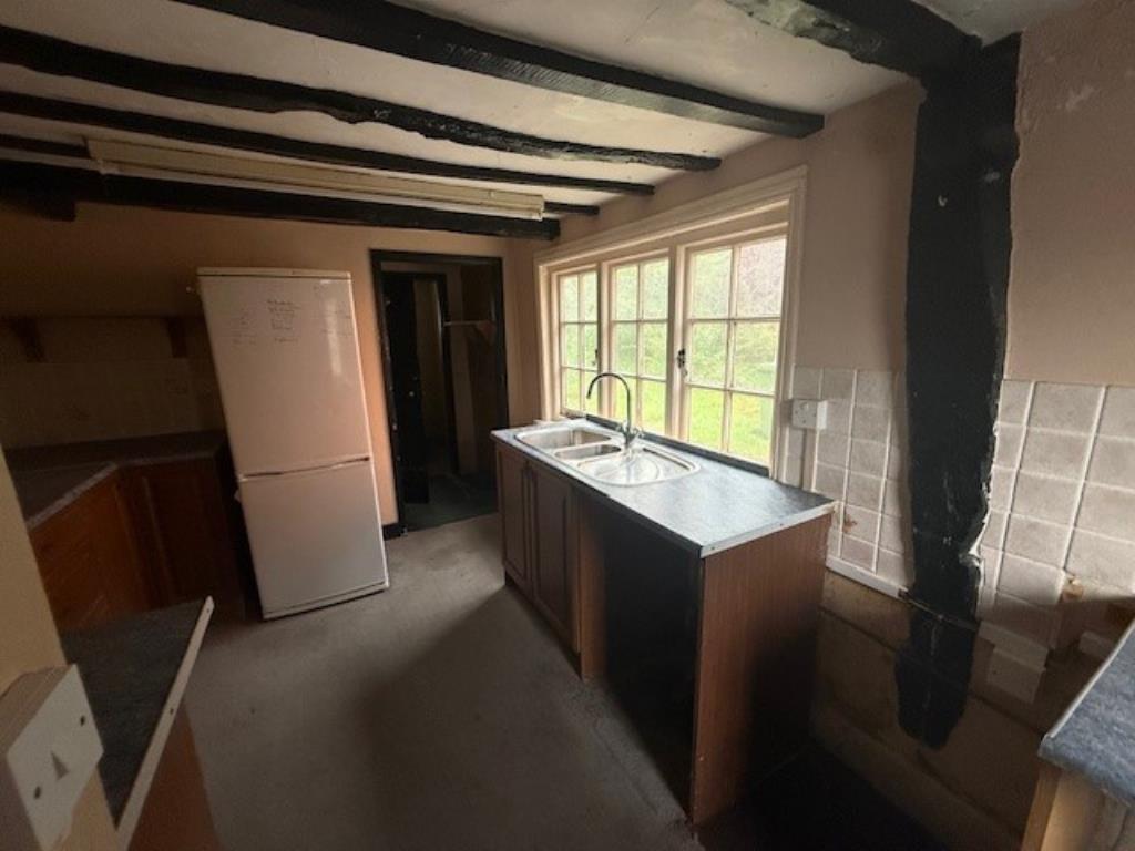 Lot: 115 - A PAIR OF THATCHED COTTAGES IN NEED OF IMPROVEMENT - 48 Abbey Street kitchen with window and wooden beams